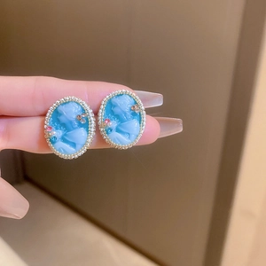 Close-up of vintage sky blue relief portrait earrings with gold edge and small pearls