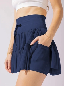 Detail of high waisted navy pleated skirt showing the built-in shorts and phone pocket