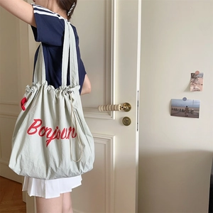 Detail of light green fabric tote bag with drawstring closure and red Bonjour text