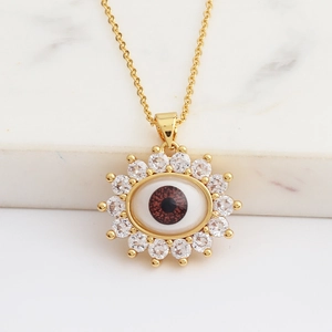 Macro shot of sunburst evil eye pendant with brown center and pave zircon stones