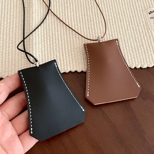 Detail of leather clochette key holder necklace with white contrast stitching in black and brown