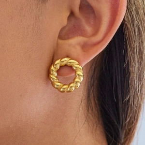 Polished gold twisted hoop earring shown on model ear for a luxury fashion look