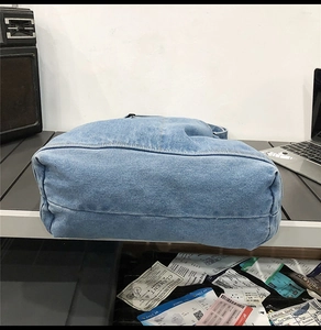 Detailed base view of washed light blue denim tote bag with reinforced double stitching