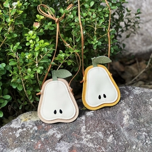 Close-up of cute pear-shaped crossbody bags in yellow and beige on outdoor stone