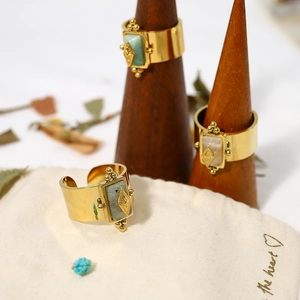 Vintage gold stainless steel rings with natural stones on a wooden display stand