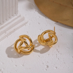 Dettaglio di orecchini a nodo intrecciato placcati oro 18K su sfondo di pietra bianca minimal