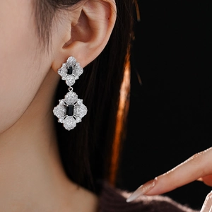 Close-up of silver flower earrings with black stones and crystals on a model