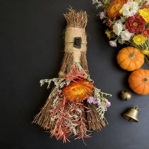 Detail of handcrafted decorative witch broom with orange dried flowers and crystal