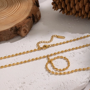 Dettaglio collana a Y placcata oro 18K con perline ovali e chiusura a moschettone su pietra