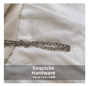 Detail showing high-quality silver chain links on white fabric for fashion handbags