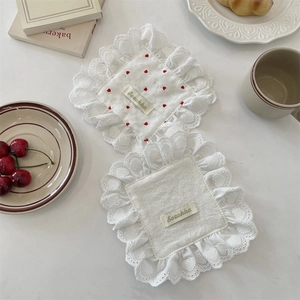 Detailed view of heart pattern napkins and white lace coasters on a tea table setting
