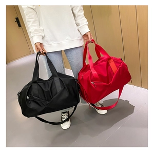Model holding black and red large capacity waterproof nylon travel bags in a hallway