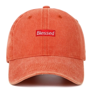 Close-up of Blessed embroidery and washed cotton texture on a vintage orange baseball cap