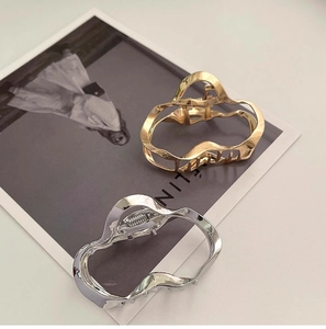 Detail view of irregular liquid metal hair claws in gold and silver on a fashion magazine