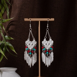 Close-up of Bohemian earrings with silver metal feathers and colorful ethnic beads