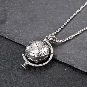 Detail of spinning globe pendant on a stainless steel box chain over dark rock
