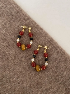 Detail of beaded earrings with agate, pearl and tiger eye on gold horseshoe studs