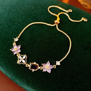 Detailed shot of adjustable gold box chain with purple zircon flowers on green velvet