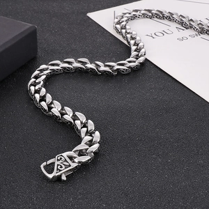Detailed macro of a punk style stainless steel Cuban chain with engraved floral clasp