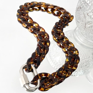 Macro detail of amber resin chain link with silver metal safety clasp closure