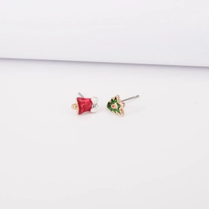 Detailed view of asymmetric Christmas stud earrings with red bells and green trees