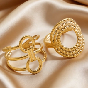 Detailed view of irregular geometric gold stainless steel rings on champagne satin fabric