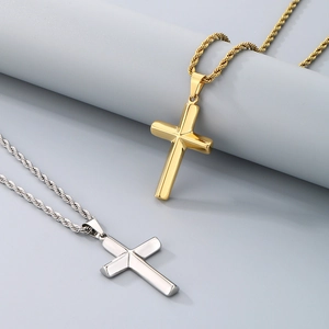 Polished gold and silver cross necklaces with rope chains on a minimalist grey backdrop
