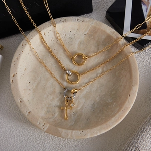 Close-up of layered 18K gold and silver stainless steel cross pendant necklaces on a tray