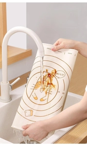 Water rinsing a silicone kneading mat with cartoon prints and circular scale markings