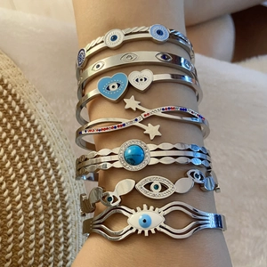 Close-up of silver evil eye bracelets with heart and star charms worn on a wrist