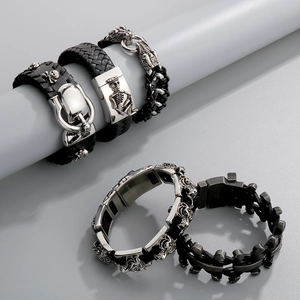 Close-up of five men's black leather bracelets with stainless steel skull and tiger charms