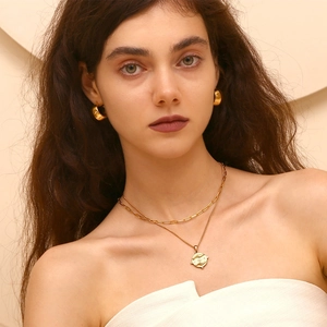 Dettaglio di modella che indossa collana tarot placcata oro 18K e orecchini a cerchio dorati