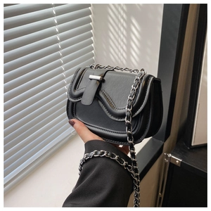 Close-up of black leather saddle bag with silver chain strap and wavy flap detail