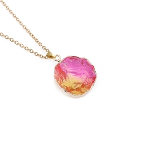 Macro shot of gold chain with oval pink and orange gradient gemstone pendant detail