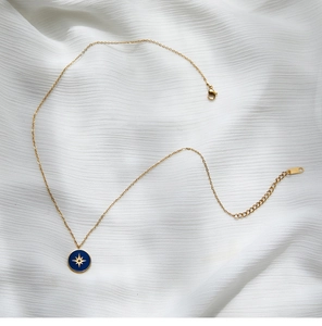 Detail of blue enamel compass star pendant on 18K gold plated stainless steel necklace