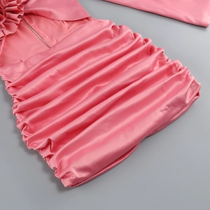 Détail d'une robe en satin rose avec d'élégants plis horizontaux et texture soyeuse