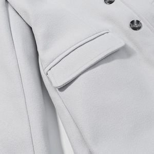 Dettaglio cappotto in lana grigio chiaro con tasca a patta e bottoni tondi scuri