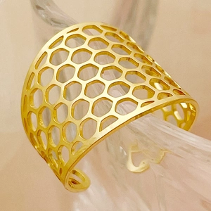 Detailed close-up of gold-plated wide open ring featuring a hollow honeycomb pattern