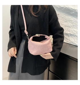 Detail of pink suede shoulder bag with gold metal buckle and matching strap on a model