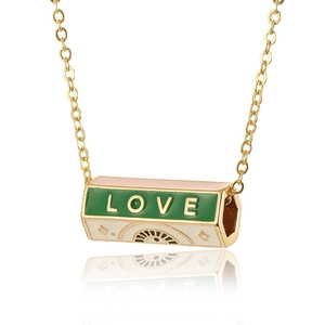 Detail view of gold hex pendant with green LOVE enamel and mystic eye motif