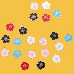 Colorful cherry blossom enamel charms for DIY jewelry making on a yellow background