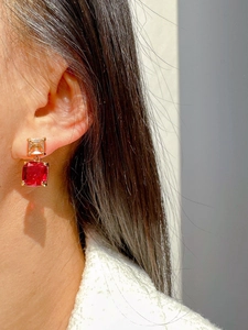 Detailed view of luxury square red and yellow crystal earrings worn on ear