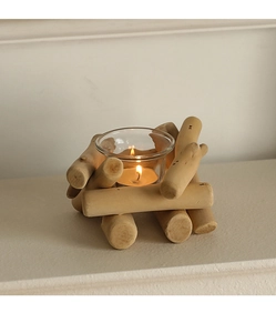 Dettaglio del portacandele in legno con bicchiere e lumino acceso su base bianca
