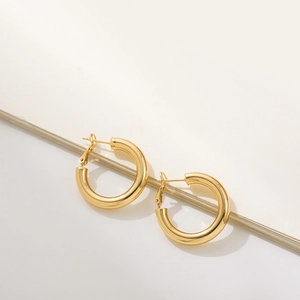 Macro detail of high-polish 18K gold hoop earrings with secure latch back closures