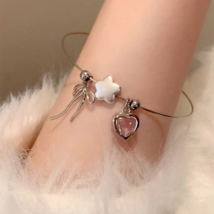 Silver bow heart star charm bracelet with pink gemstone on white faux fur