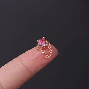 Macro shot of rose gold heart-shaped pink zircon stud earring held between fingertips