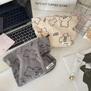 Flat lay of corduroy cosmetic bags with bear prints and daily accessories on desk