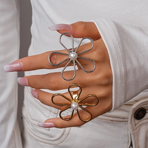 Detailed view of oversized hollow flower ring with faux pearl on model's hand