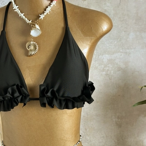 Close-up of black halter bikini top with ruffled hem on mannequin for beachwear