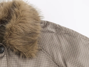 Detail of faux fur collar and brown checkered fabric with dark buttons on a trench coat
